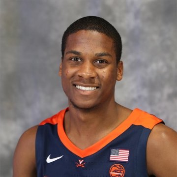 Chase Coleman, wearing a UVA basketball jersey, smiles at the camera in front of a gray backdrop