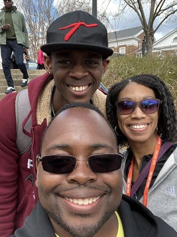 Isaac Henderson, wearing a hat, stands with his father and his mother.