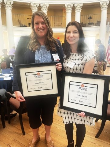 Anne Jewett stands next to Jamie Jirout in the Rotunda Dome Room, both holding certificates.